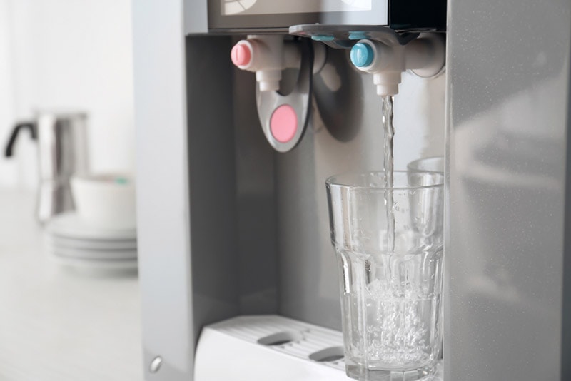 filling glass with water from modern cooler