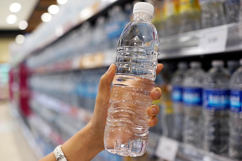 hand holding a bottle of water or mineral water in grocery store