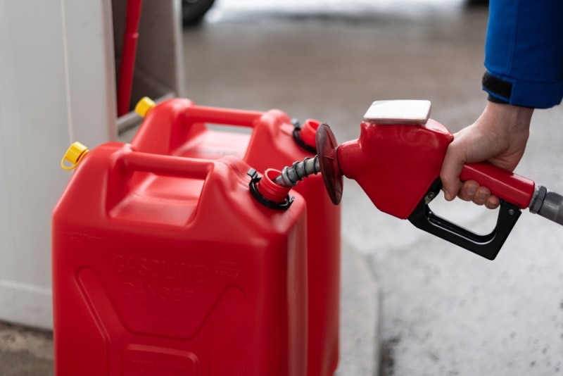 man filling gasoline on red container
