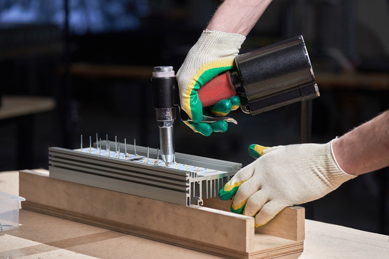 man installs a rivet with a pop rivet gun