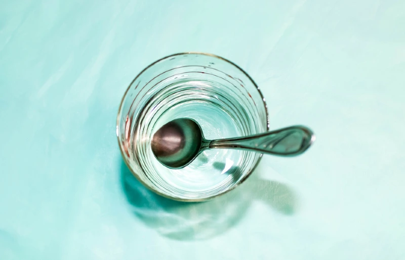transparent glass with water and spoon in it