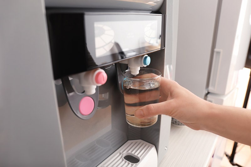 woman filling glass from water cooler