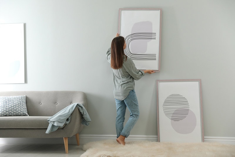 woman hanging or removing picture on the wall