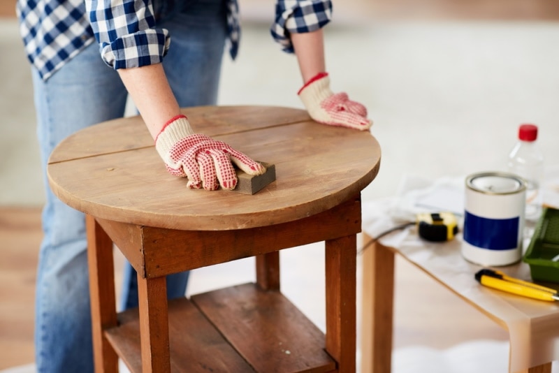 woman sanding old wooden table
