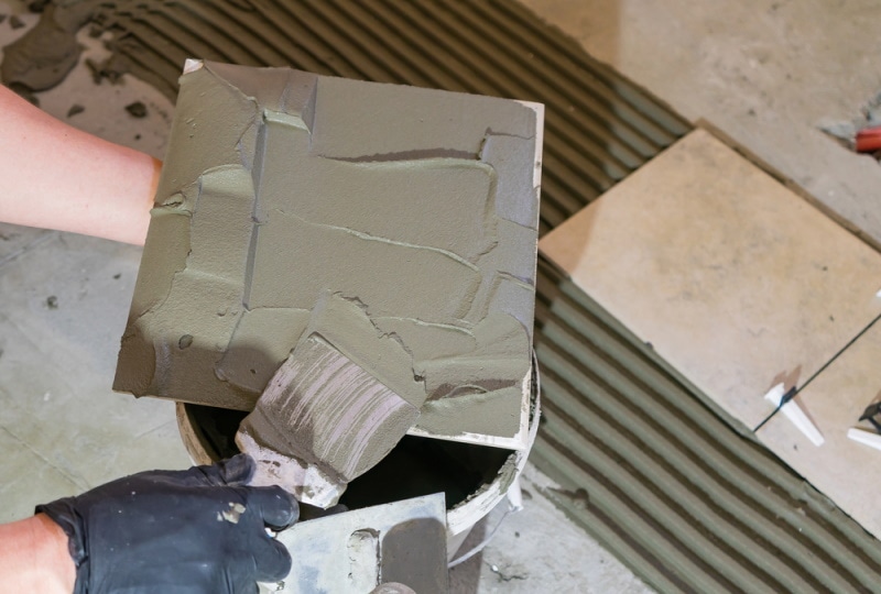 worker applying thinset mortar on tiles