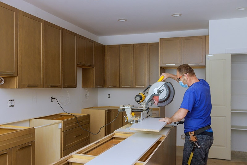 worker cutting wood for kitchen cabinets