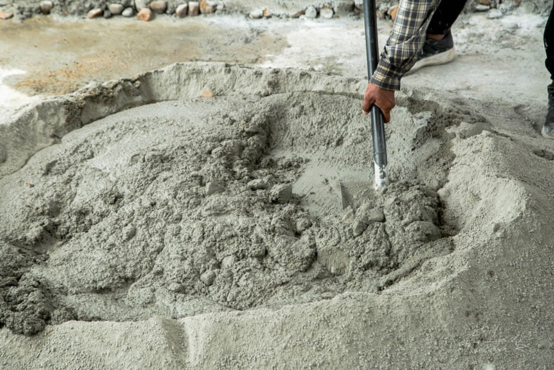worker mixing cement with sand