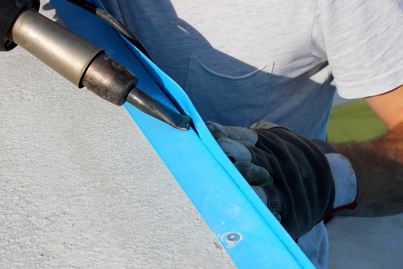 worker welds plastic cover for water pool