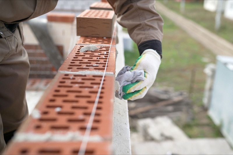 Bricklayer wiping excess mortar from bricks