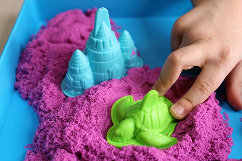 Fun kinetic sand. Child building sandcastle