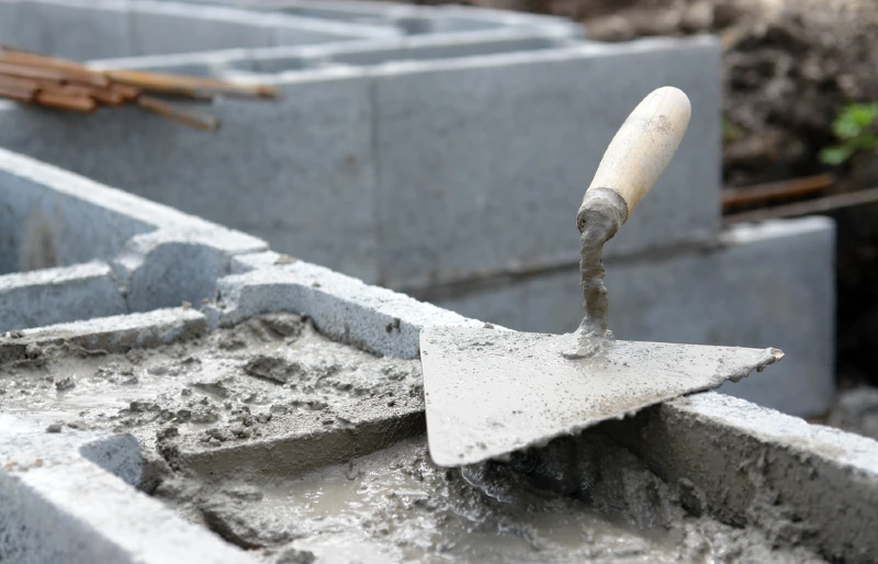 close up of trowel on concrete blocks filled with mortar