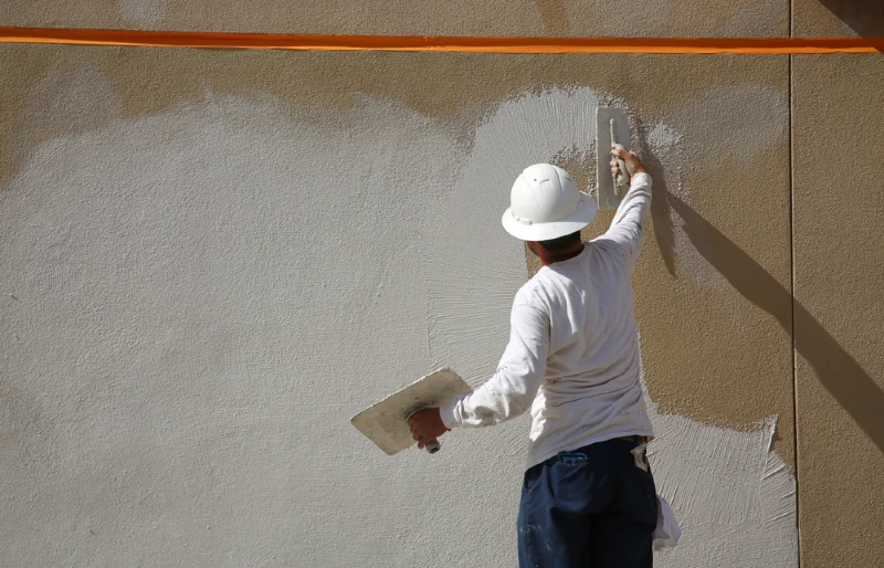 construction worker applying stucco on outer wall