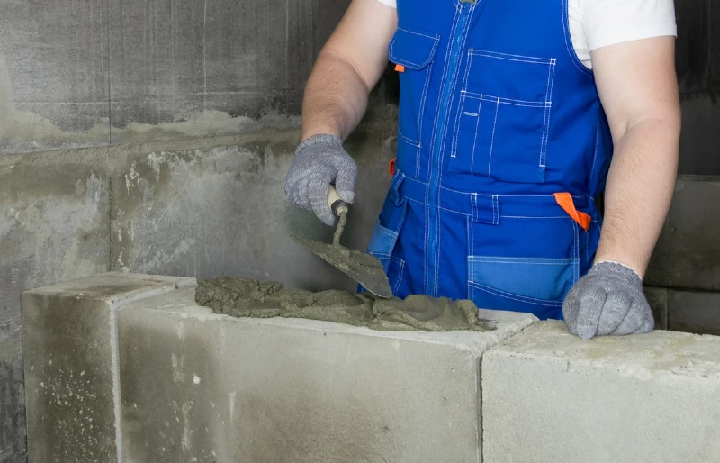construction worker laying blocks with mortar cement