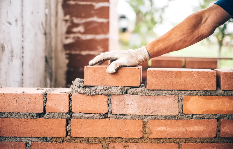 construction worker laying bricks with mortar