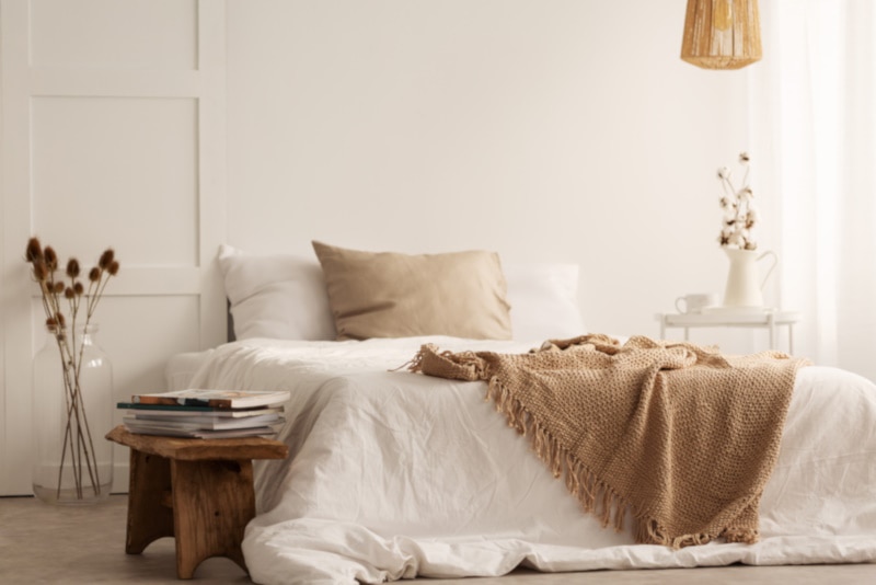 Blanket on white bed in natural bedroom interior