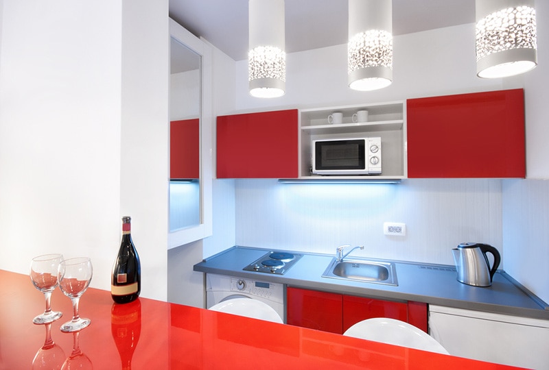 Modern hotel room or studio flat kitchen counter with appliances and a bottle of wine with glasses interior design