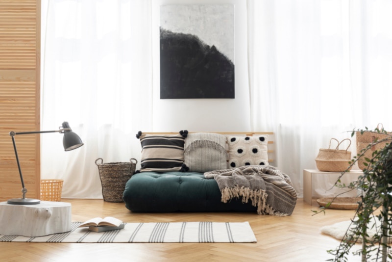 Poster above green futon with patterned pillows