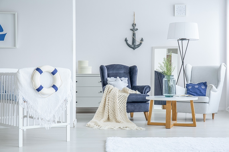 Vase with white flowers standing on a small table in bright bedroom for a toddler in marine style