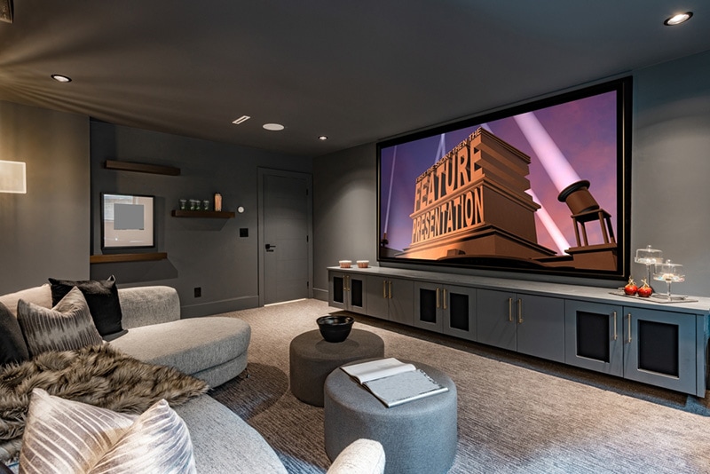 home theatre with low lighting grey furnishings large projection screen and popcorn