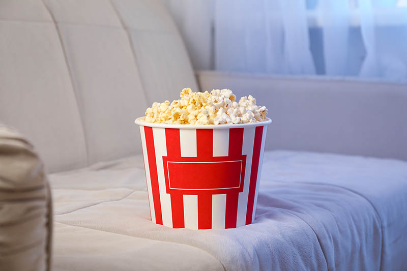 Bucket of popcorn on sofa