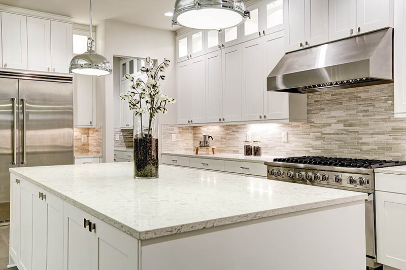 Gourmet kitchen features white shaker cabinets with marble countertops