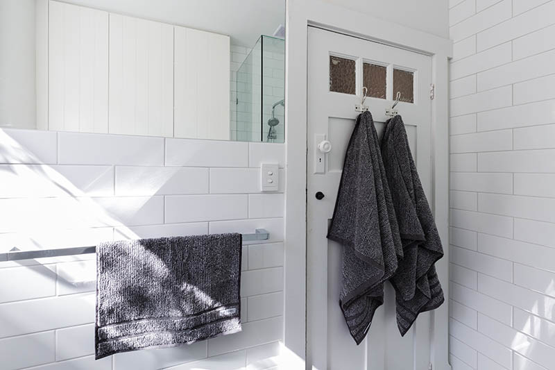 Luxury towels on door hooks in modern white bathroom with brick pattern subway tiles
