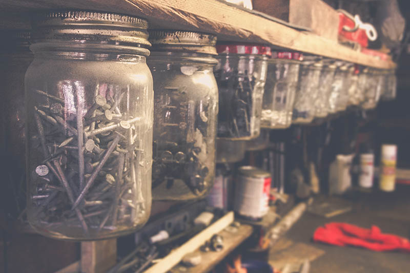 Mason jars filled with various nails and screws hanging in an orderly fashion in a workshop