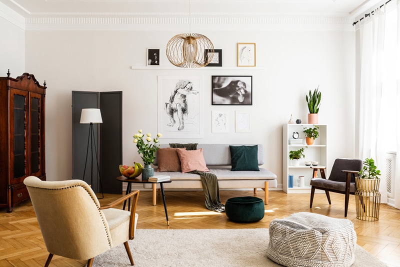 Stylish beige armchair and pouf on the cozy carpet in classy living room interior
