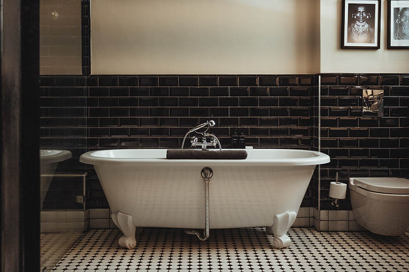 Timeless beauty with this black and white bathroom with freestanding tub and black glossy tiles