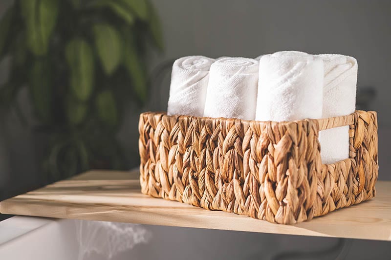 White bath towels rolled in woven jute basket