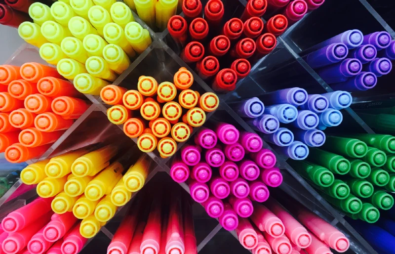 colored pens in shelves with diagonal partitions
