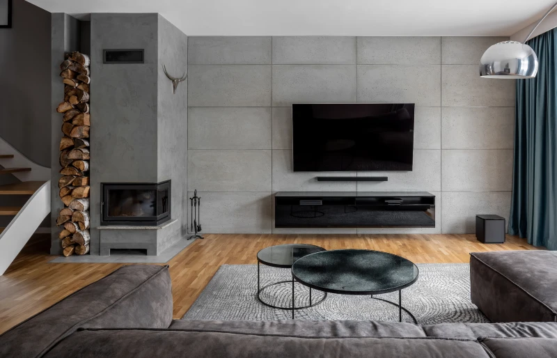 modern living room with floating shelves and TV mounted on cement wall