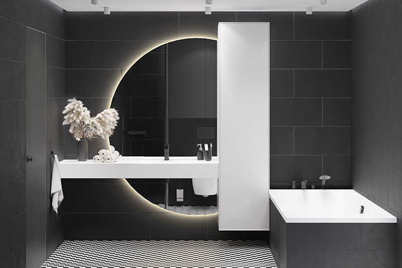 Black and white bathroom with large illuminated round mirror