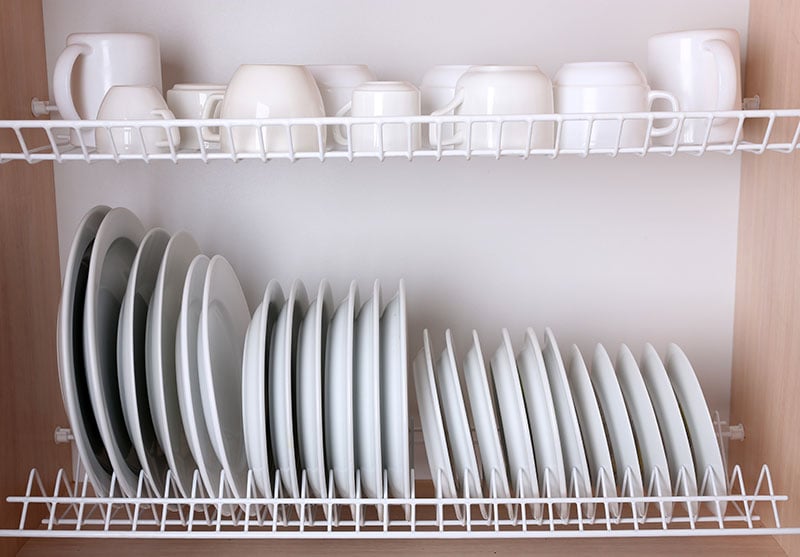 Clean dishes drying on metal dish rack on shelf