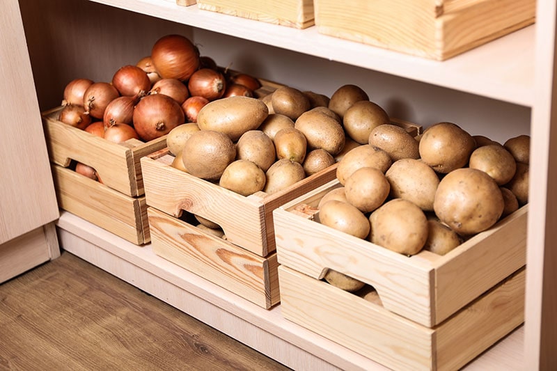 Crates with potatoes and onions on shelf