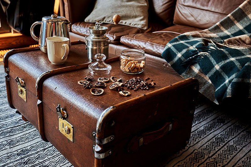Cup of coffee, coffeepot and coffee beans on vintage suitcase design in colonial style