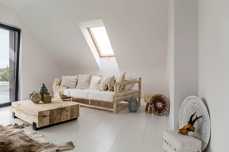 Decorative lantern and vase on wooden table between beige sofa and fur on floor in rustic living room