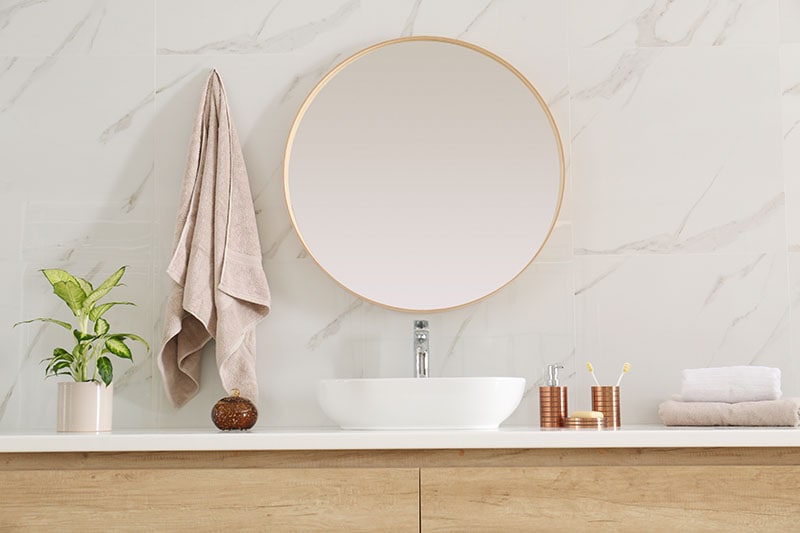 Round mirror over vessel sink in stylish bathroom interior