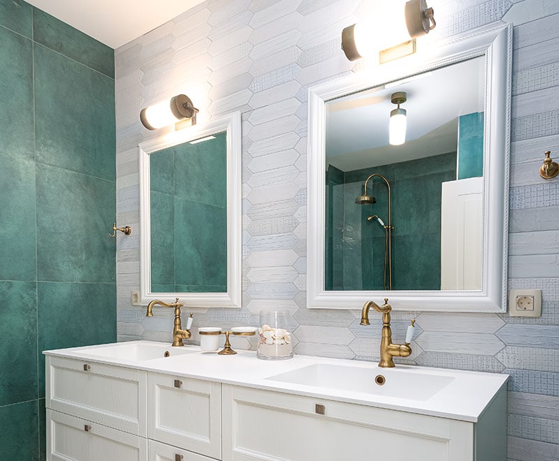 Small bathroom with two sinks with green and light blue tiles