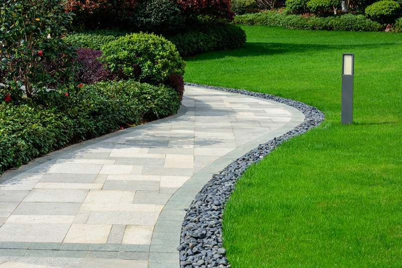There is a black stone garden on the edge of the curved path