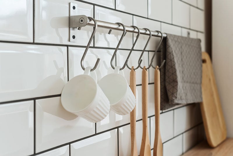 Two white cups, cutlery on hook and dishes in the white modern kitchen